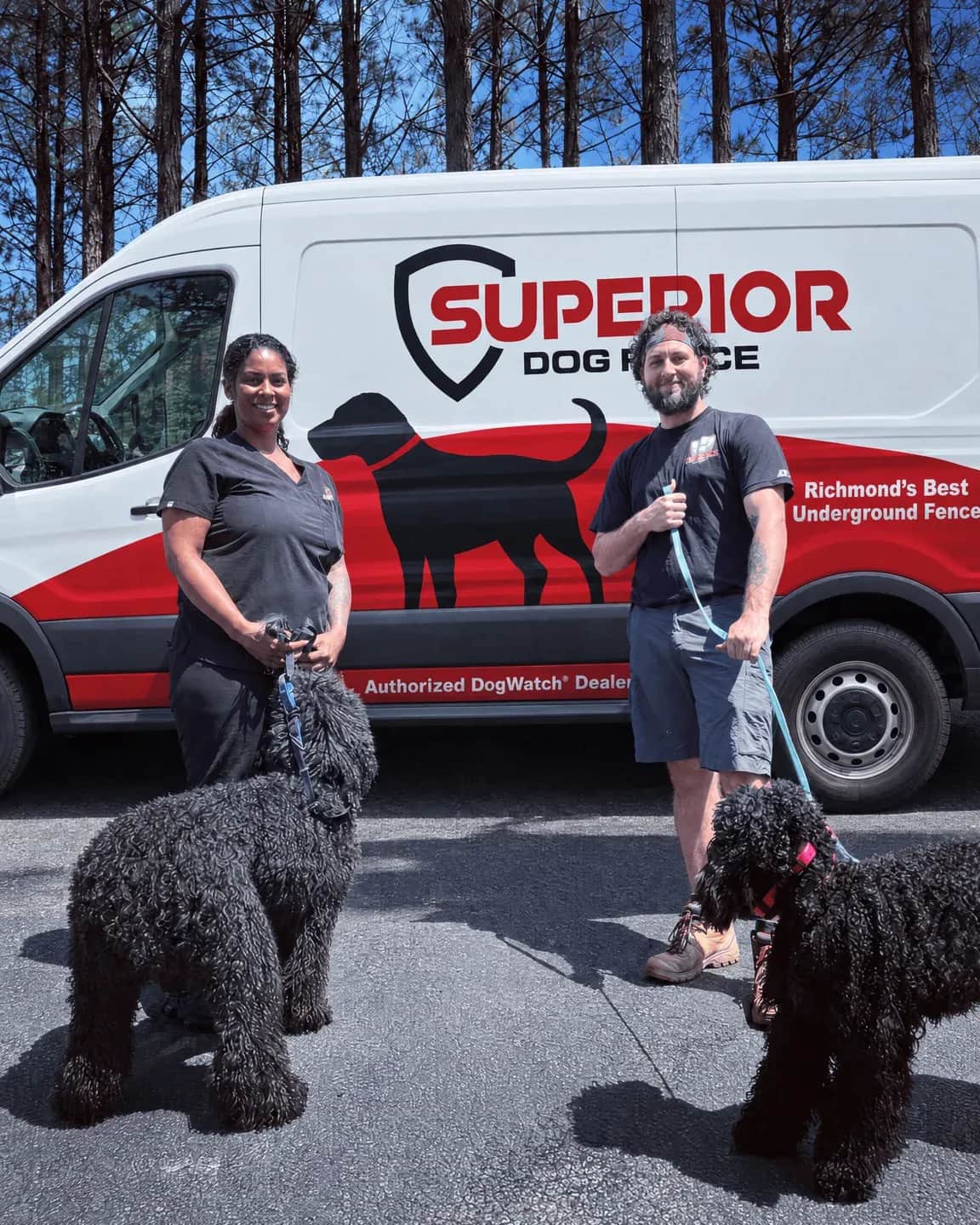 Two people with two black poodles beside the Superior van.